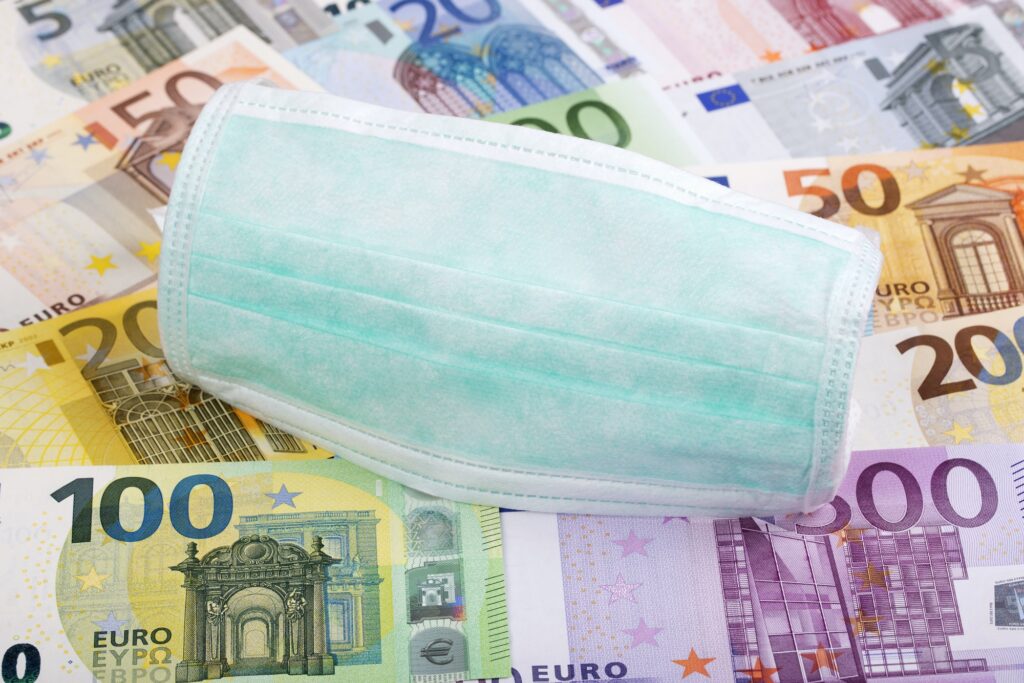 Medinzinische Mund-Nasen-Maske auf unterschiedlichen Euroscheinen liegend