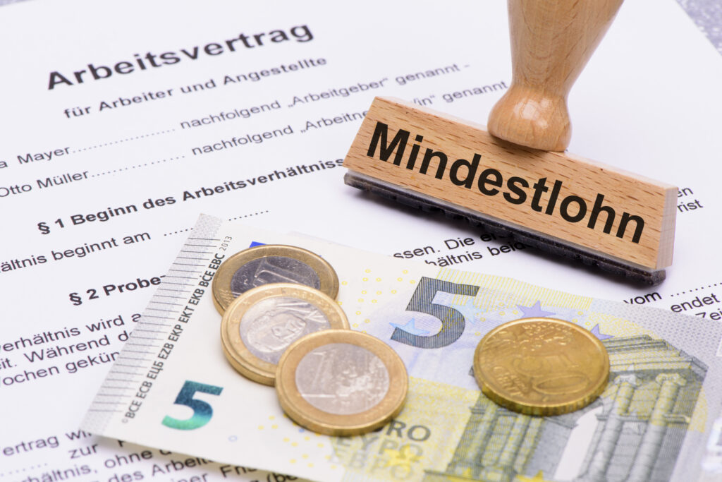 Mindestlohn von 8,50 Euro in Deutschland, symbolisiert durch Münzen und Geldschein mit Mindestlohn-Stempel
