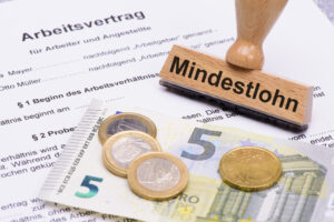 Mindestlohn von 8,50 Euro in Deutschland, symbolisiert durch Münzen und Geldschein mit Mindestlohn-Stempel
