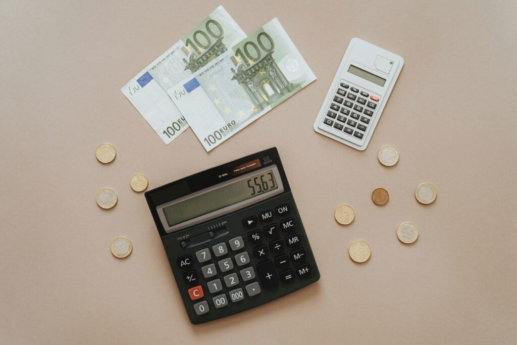 Taschenrechner, Geldscheine und Münzen liegen auf einem Tisch