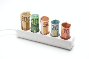 Electric plug strip with banknotes on white background, concept spending electrical energy
